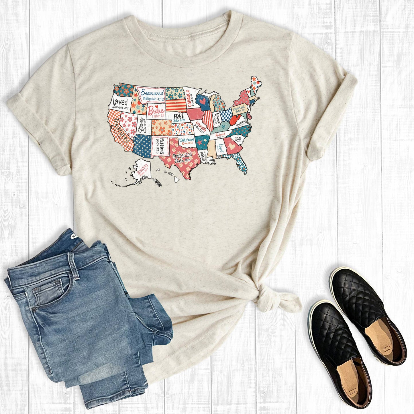 Beige t-shirt with USA map design, paired with blue jeans and black shoes on a light wooden surface.