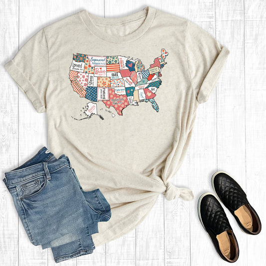 Beige t-shirt with USA map design, paired with blue jeans and black shoes on a light wooden surface.