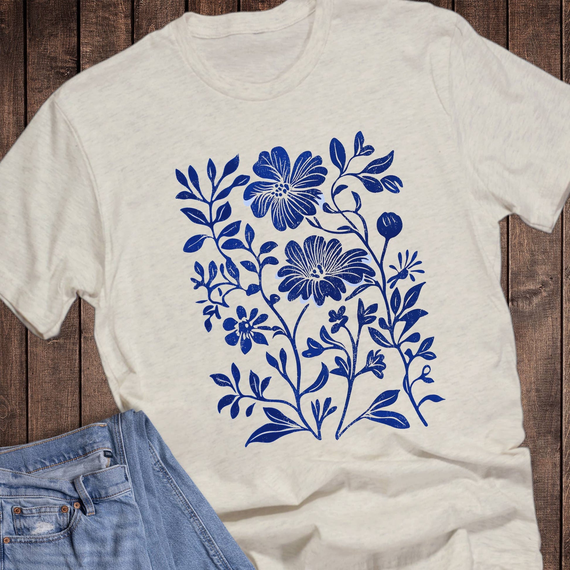White t-shirt with blue floral design on a wooden surface
