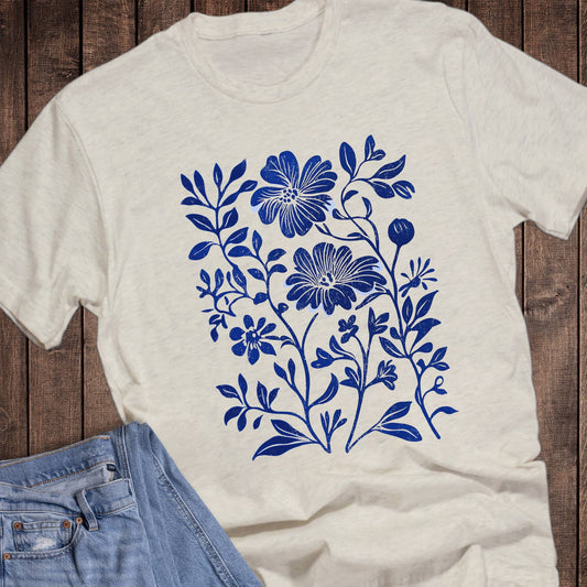 White t-shirt with blue floral design on a wooden surface